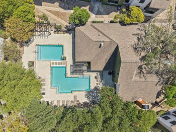 A large house with a pool surrounded by trees.